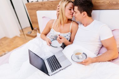 Çift yatakta kahve ve dizüstü bilgisayar ile rahatlatıcı