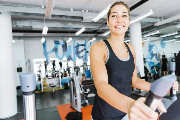 Mujer en forma joven usando un entrenador elíptico — Foto de Stock