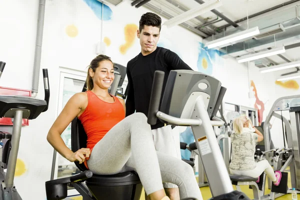 Woman instructed by a handsome man in a gym — Stock Photo, Image
