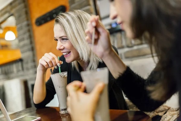 Дві жінки п'ють і розмовляють у кафе — стокове фото