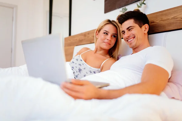 Felice coppia a letto utilizzando il computer portatile — Foto Stock