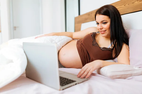 Zwangere vrouw met laptop in bed — Stockfoto