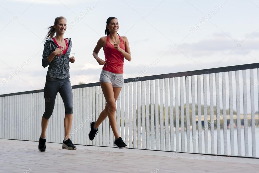 Two sporty women jogging in city