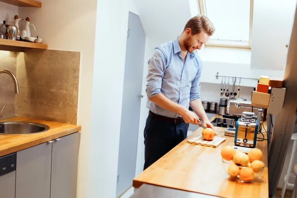 Mann schneidet Orangen in Küche — Stockfoto
