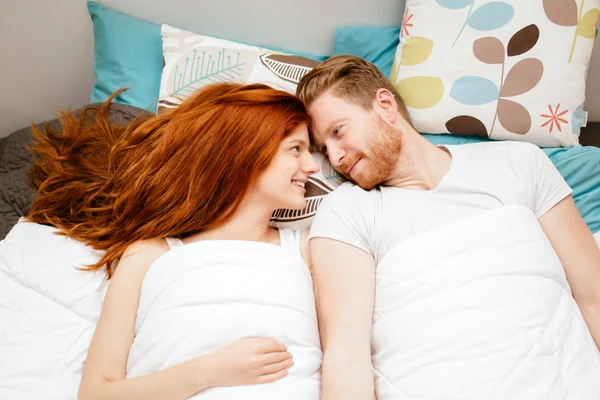 Hermosa pareja sonriendo en la cama — Foto de Stock