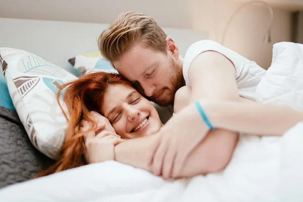 Schönes Paar lächelt im Bett — Stockfoto