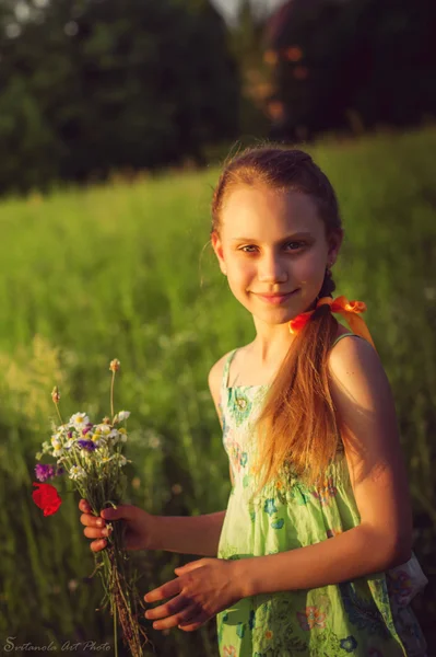 Menina em um campo com um buquê de flores — Fotografia de Stock