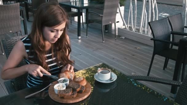 Flickan äter en bagel och dricker kaffe — Stockvideo