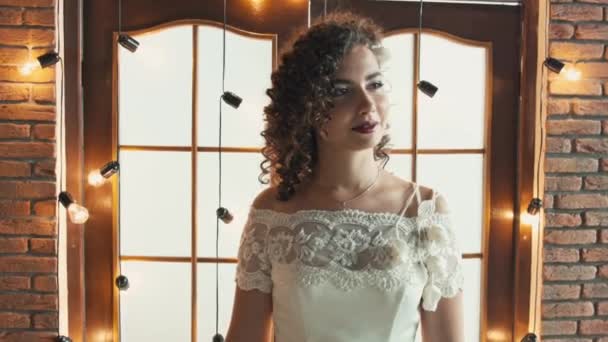 La chica en un vestido de novia sonriendo y mirando de lado a lado — Vídeos de Stock