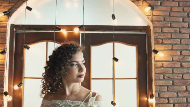 La chica en un vestido de novia sonriendo y mirando de lado a lado — Vídeos de Stock