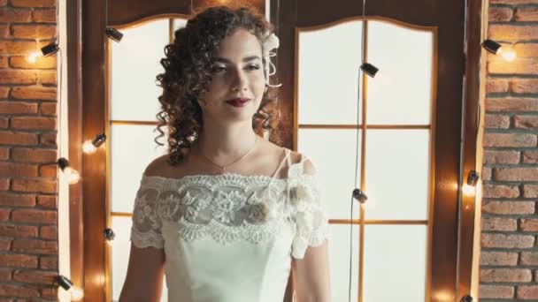 La chica en un vestido de novia sonriendo y mirando de lado a lado — Vídeos de Stock