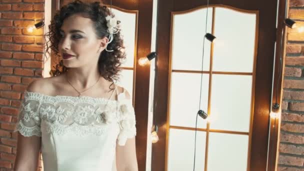 La chica en un vestido de novia sonriendo y mirando de lado a lado — Vídeos de Stock