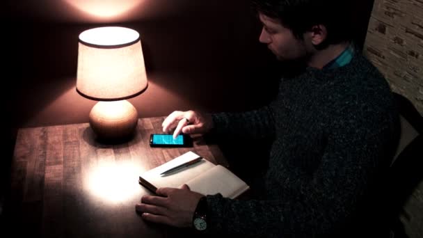 Der Mann mit dem Smartphone-Stift schreibt in Notizbuch — Stockvideo