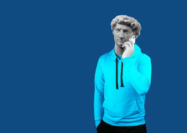 Modern sanat kolajı. Uygulama mesajlaşması mesajı kullanarak cep telefonu tutan bir adamın portresi. David 'in alçıtaşı başı. Takım elbiseli adam. Mavi bir arkaplanda.