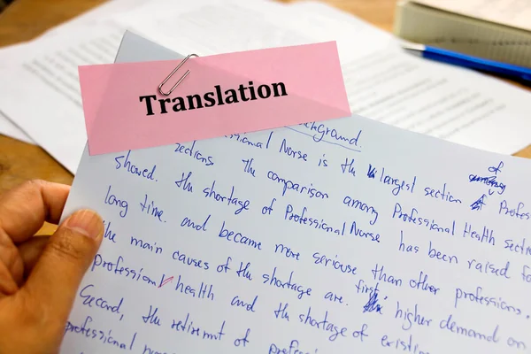 Translation paper in hand over wooden desk — Stock Photo, Image