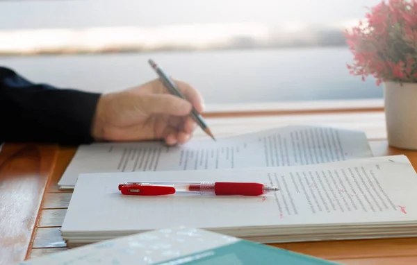red pen on blurred paperwork and books on wooden table in office