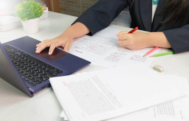 Kırmızı kalemi beyaz masadaki düzeltme kağıdının üzerinde tutarken