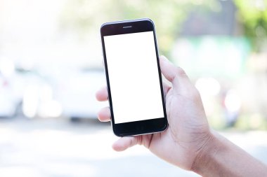 Metin mesajınız veya bilgi içeriğiniz için boş ekranlı akıllı telefonu tutan erkek eli görüntüsü, şehir ortamında cep telefonundan mesaj okuyan kadın görüntüsü. 