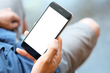 Metin mesajınız veya bilgi içeriğiniz için boş ekranlı akıllı telefonu tutan erkek eli görüntüsü, şehir ortamında cep telefonundan mesaj okuyan kadın görüntüsü. 