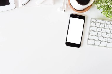 Not defteri, dizüstü bilgisayar ve kahve fincanı fare notlu üst görünüm ofis malzemeleri. Boş ekran cep telefonu ve beyaz masa çalışma alanı üzerindeki malzemeler ve kopyalama alanı..