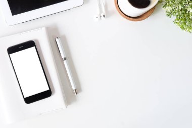 Not defteri, dizüstü bilgisayar ve kahve fincanı fare notlu üst görünüm ofis malzemeleri. Boş ekran cep telefonu ve beyaz masa çalışma alanı üzerindeki malzemeler ve kopyalama alanı..