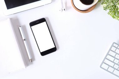 Not defteri, dizüstü bilgisayar ve kahve fincanı fare notlu üst görünüm ofis malzemeleri. Boş ekran cep telefonu ve beyaz masa çalışma alanı üzerindeki malzemeler ve kopyalama alanı..