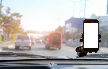 Kesilmiş görüntü. Şoför araba kullanırken telefonu kullanıyor. Yuvarlak kenarlı modern akıllı telefon. Model için izole ekran. Arka planda araba navigasyon görüntüsü. 