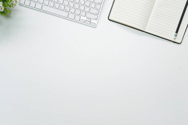 Boş defterli beyaz ofis masası, bilgisayar klavyesi ve diğer ofis malzemeleri. Kopyalama alanı ile, düz yatar.