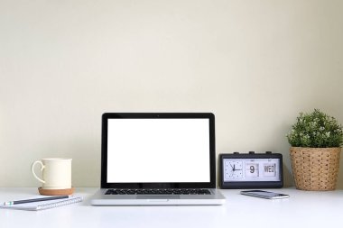 Minimal workspace with white screen computer and office supplies on white table.	