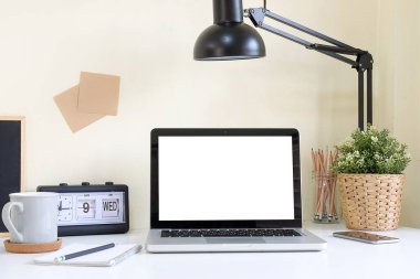 Minimal workspace with white screen computer and office supplies on white table.	