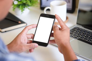 Cropped shot of young man using smart phone with white screen while sitting in modern office.	