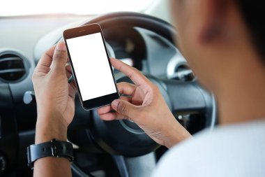 Kesilmiş görüntü. Şoför araba kullanırken telefonu kullanıyor. Yuvarlak kenarlı modern akıllı telefon. Model için izole ekran. Arka planda araba navigasyon görüntüsü. 