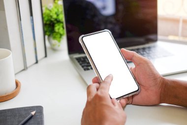 Modern ofisin bulanık arka planına sahip akıllı telefon kullanan erkek elleri yakın plan görüntüsü. Grafik görüntüleme için boş ekran monitörü.