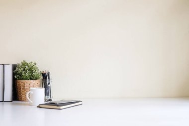 Boş çerçeve, kahve fincanı ve kalem tutacağı ahşap masa ve tuğla duvarlı.