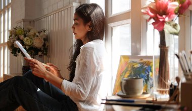 Resim stüdyosunda suluboya resimlerle resim yapan güzel bir bayan ressam..