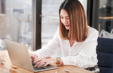 Modern iş yerinde bilgisayar tabletleriyle çalışan gülümseyen genç iş kadını.