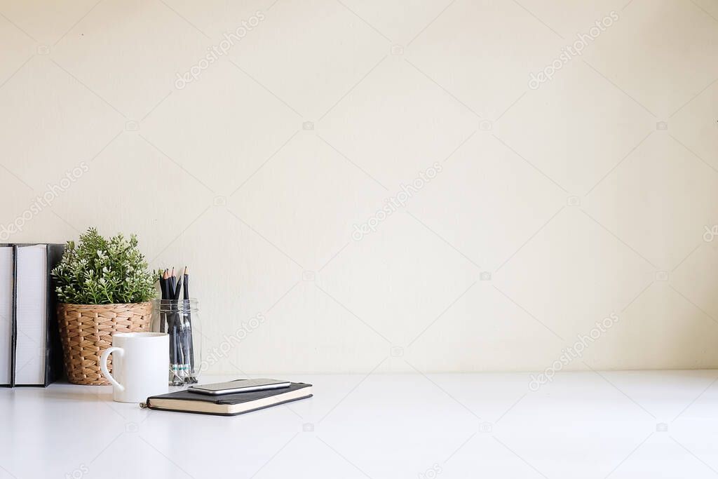 Empty picture frame, coffee cup and pencil holder on wooden table with brick wall.