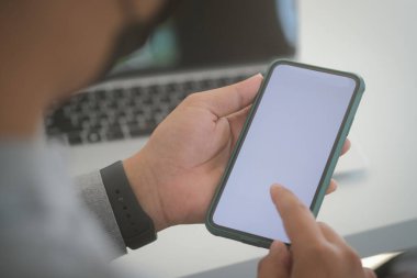 Mock up smartphone of hand holding black mobile phone with blank white screen.	