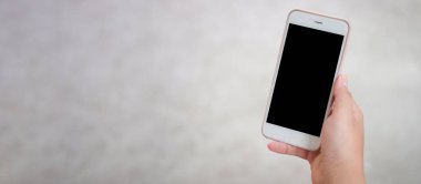 Mock up smartphone of hand holding black mobile phone with blank white screen.	