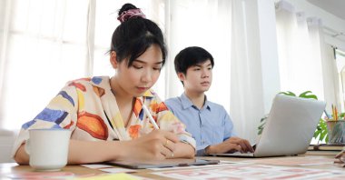 İş kavramının işe yaraması ve insanların mutlu işleri bilgisayarlı yaratıcı kadın ofis çalışanı belgelerle ve dizüstü bilgisayarlarla deftere yazı yazıyor..