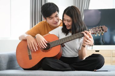 Genç çift evdeki oturma odasında dijital tablet ekrana bakarken rahat koltukta dinleniyor..