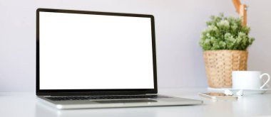 Boş ekran, bitki ve kahve bardağını beyaz masaya koyan bir bilgisayar dizüstünü kapat.