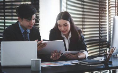 Business people analysing and discussing online data with laptop computer in office.	