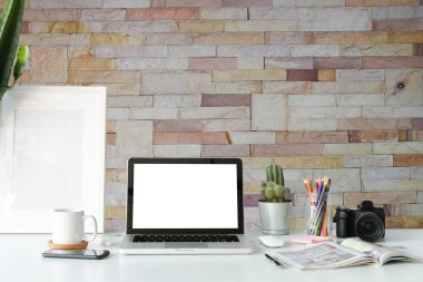 Simple workspace with computer, equipment and brick wall background.	