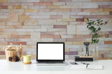 Simple workspace with computer, equipment and brick wall background.	