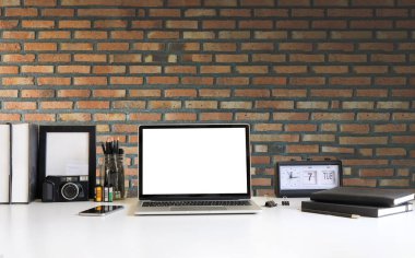Simple workspace with computer, equipment and brick wall background.	