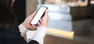 Genç kadın ellerinin çalışma odasındaki beyaz ekranlı akıllı telefonu taklit edişinin yakın görüntüsü..