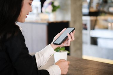 Genç kadın ellerinin çalışma odasındaki beyaz ekranlı akıllı telefonu taklit edişinin yakın görüntüsü..