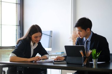 İş adamları ofisteki dizüstü bilgisayarla çevrimiçi verileri analiz ediyor ve tartışıyor.