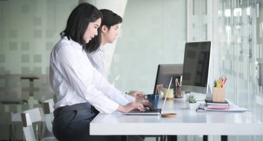 Resmi kıyafetler giyen iki iş adamı ofiste mali evrakları tartışıyor..